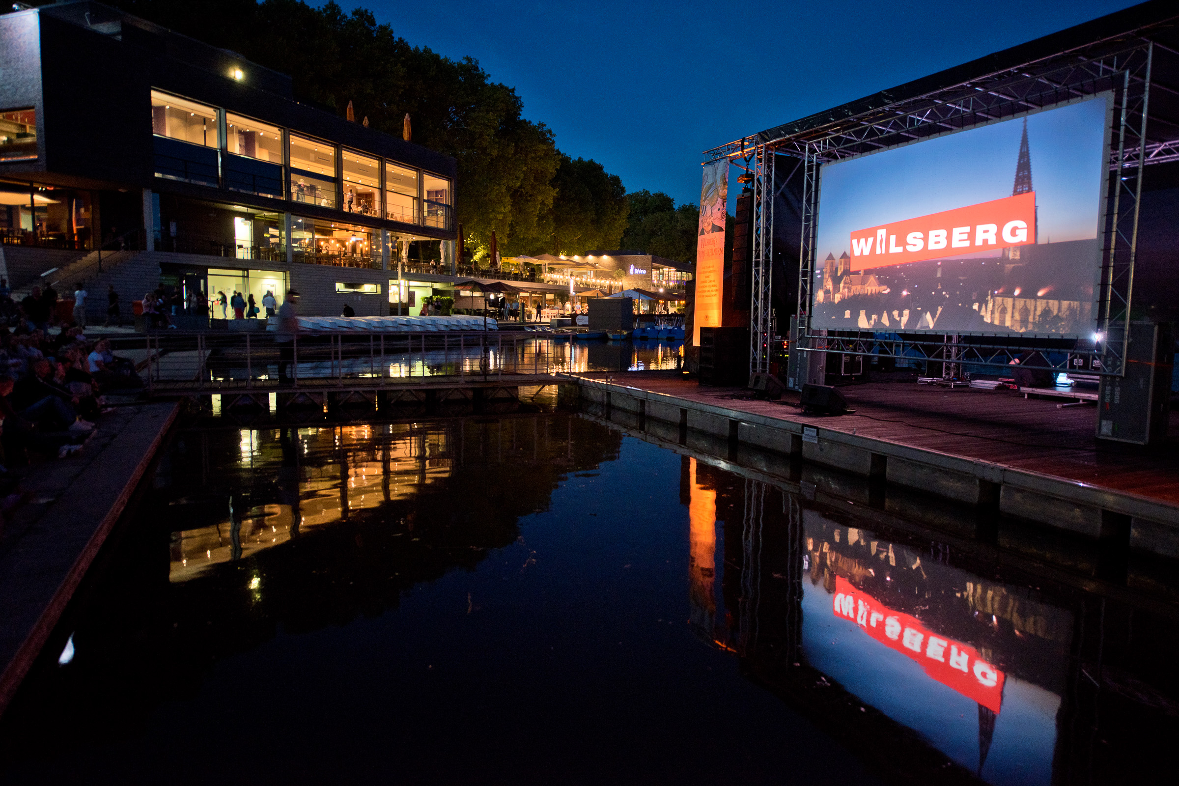 Die beleuchtete Wilsberg-Leinwand spiegelt sich bei der Open-Air-Filmvorführung im Aasee.